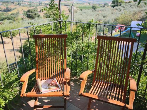 - deux chaises en bois assises sur un balcon avec un magazine dans l'établissement Belvilla by OYO Glicine, à Gualdo Cattaneo