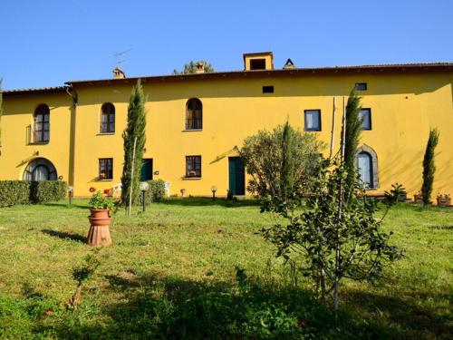 ヴィンチにあるBelvilla by OYO Da Vinci Dueの野原の木々が植えられた大きな黄色の建物