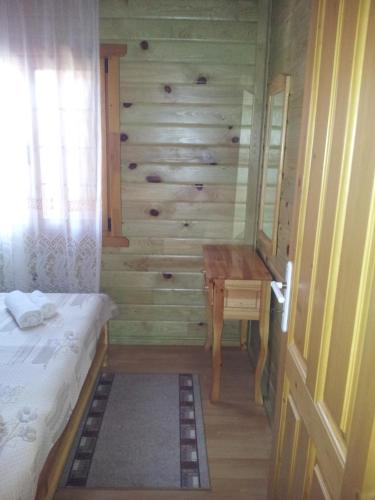 a bedroom with a bed and a wooden wall at Zlatnoto Pile Restaurant & Rooms in Kranevo
