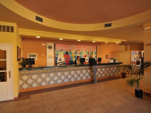 a man standing at a bar in a hotel lobby at Belvilla by OYO Comte de Empuries Apt C in Empuriabrava