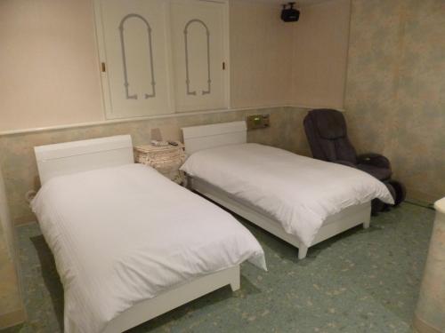 a room with two beds and a chair at Hotel Sha La La in Okinawa City