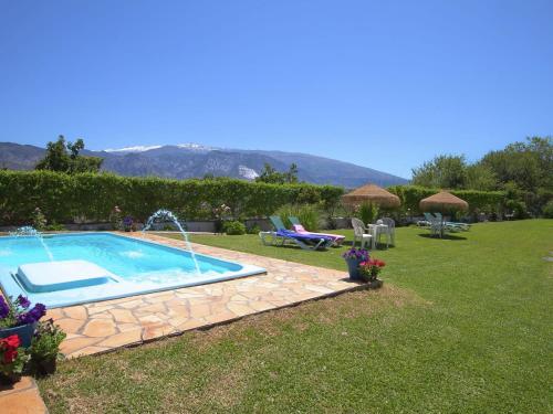 a backyard with a swimming pool and a lawn with flowers at Belvilla by OYO Molinos de Padul Se a Anica in Padul