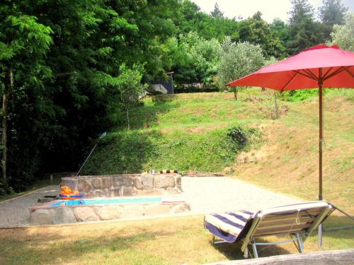 einen roten Regenschirm und einen Stuhl neben einem Pool in der Unterkunft Belvilla by OYO Olivi Rosso in San Quirico