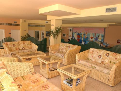 Belvilla by OYO Comte de Empuries Apt B في إمبوريابرافا: غرفة معيشة مع كنب وطاولات الخوص