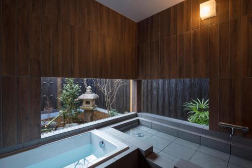 a bath tub in a bathroom with a window at Yoitsubaki Machiya House in Kyoto