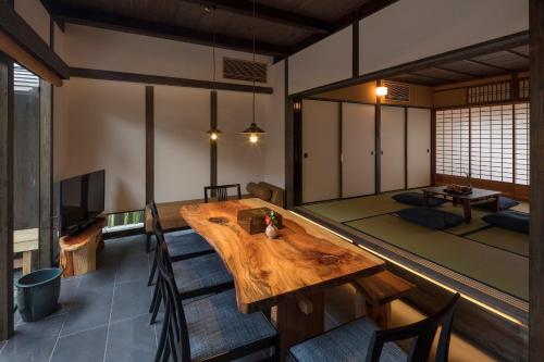 a room with a wooden table and a living room at Yoitsubaki Machiya House in Kyoto