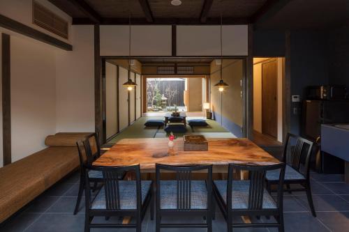 a dining room with a wooden table and chairs at Yoitsubaki Machiya House in Kyoto