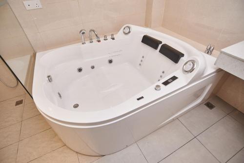 a large white bath tub in a bathroom at Corsica Hotel in Kulai