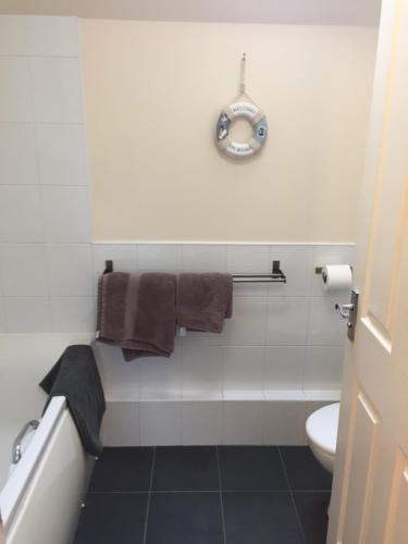 a bathroom with a toilet and a clock on the wall at 6 Varis Apartments in Forres