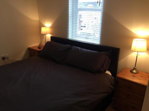 a bedroom with a bed with two lamps and a window at 6 Varis Apartments in Forres