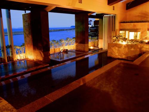 a swimming pool in a building with a view of the ocean at Hotel New Awaji in Sumoto