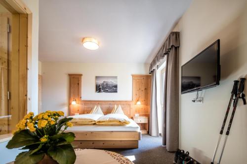 1 dormitorio con 1 cama y TV en la pared en Hotel Landgasthof Lärchenwald, en Collepietra
