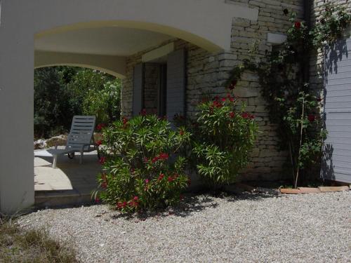 une maison avec une terrasse fleurie et une chaise dans l'établissement Le Logis, à Gordes