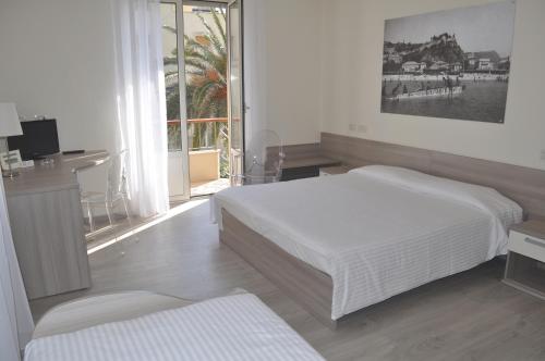 a bedroom with a bed and a desk and a window at Hotel Boncardo in Finale Ligure