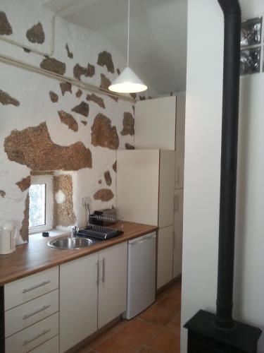 a kitchen with a sink and a stone wall at Quinta da Barroquinha in Vale de Prazeres