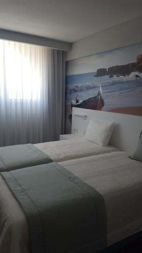 two beds in a hotel room with a window at Golden Beach Guest House & Rooftop Bar in Faro