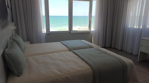 a bedroom with a bed with a view of the ocean at Golden Beach Guest House & Rooftop Bar in Faro