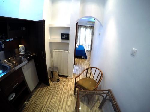 a small room with a chair and a kitchen at Atlantis Hotel in Agios Nikolaos