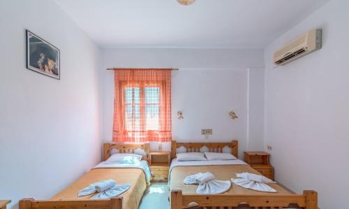 two beds in a room with a window at Hotel Eva Marina in Matala