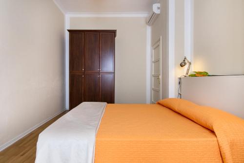 ミラノにあるApartment Papiniano 38のクローゼット付きの客室で、オレンジと白のベッド1台を利用できます。