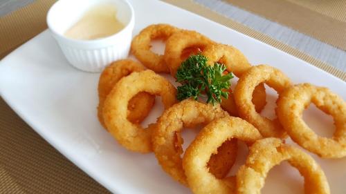 a white plate of onion rings with a garnishment at The Bedroom Ladprao 101 Bangkok - SHA in Bangkok
