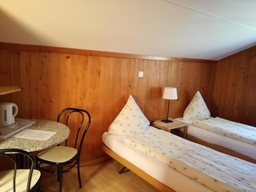a small room with two beds and a table at Gasthof Schoenegg B&B in Goldswil