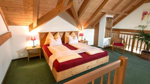 - une chambre avec un grand lit dans une pièce dotée de plafonds en bois dans l'établissement Landhaus Leitner am Wolfgangsee, à Sankt Gilgen