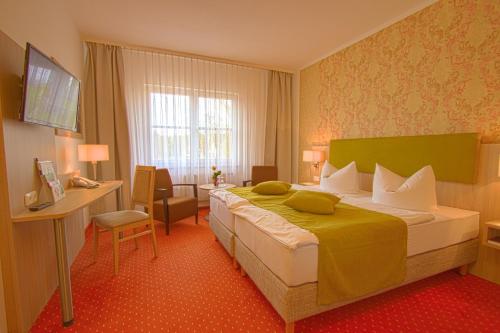 a hotel room with a large bed and a desk at Falk Seehotel Plau am See in Plau am See