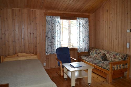 a bedroom with a bed and a couch and a window at Ruoke Holiday Village in Kesälahti