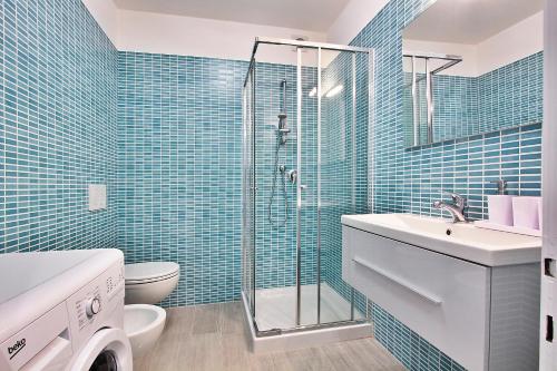 W łazience z prysznicem znajdują się niebieskie ściany wyłożone kafelkami. w obiekcie Condominio Libeccio w Lignano Sabbiadoro