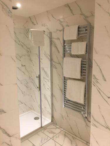 a bathroom with a shower with a mirror and towels at Virginia Court Hotel in Cromer