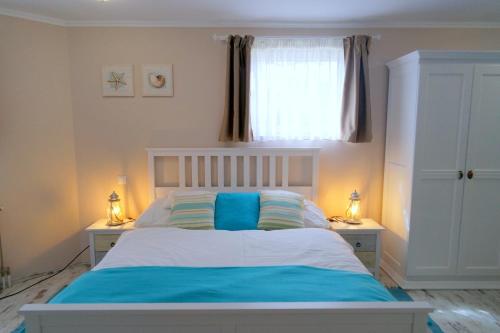 a bedroom with a bed with blue sheets and a window at Barackvirág Vendégház in Tihany