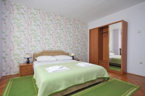 a bedroom with a green bed with a mirror at Apartments Balic in Sveti Stefan