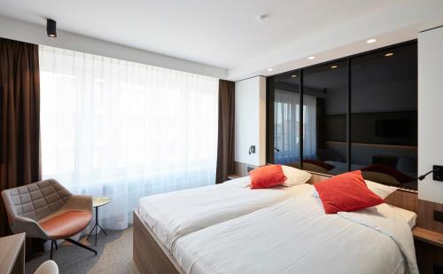 a bedroom with a large bed with red pillows at Hotel Nelson in Knokke-Heist