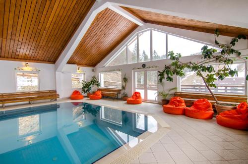 an indoor swimming pool with orange chairs and a large ceiling at Resort Cheile Gradistei Moieciu in Moieciu de Sus