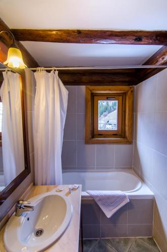 a bathroom with a sink and a tub and a window at Resort Cheile Gradistei Moieciu in Moieciu de Sus