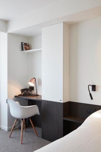 a bedroom with a bed and a desk and a chair at Hotel Nelson in Knokke-Heist