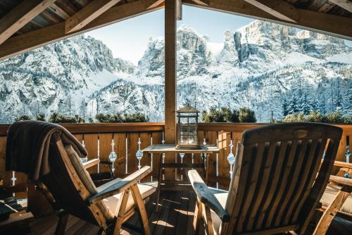 Kolfuschgerhof Mountain Resort في كولفوسكو: كرسيين على شرفة مطلة على الجبال