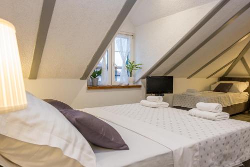 a attic bedroom with two beds and a television at XIV Century Rooms in Kaštela