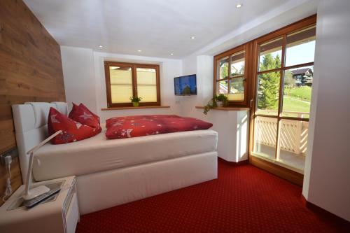 a living room with a white couch with red pillows at Gästehaus am Berg in Hirschegg