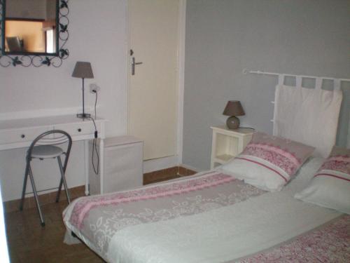 a bedroom with a bed and a desk and a chair at T2 dans maison de village in Ganges