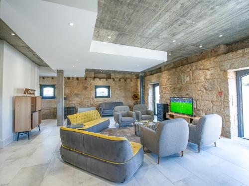 a lobby with couches and a tv and a stone wall at Borralha Hotel, Restaurante & Spa in Vila Real