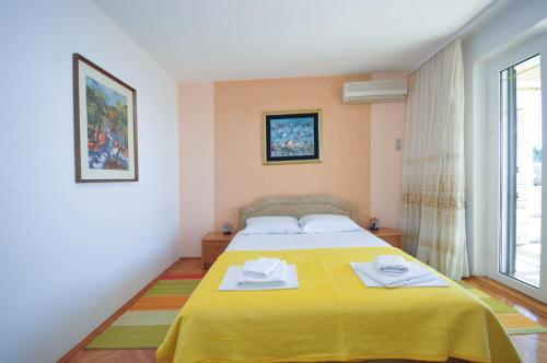 a bedroom with a yellow bed with towels on it at Apartments Balic in Sveti Stefan