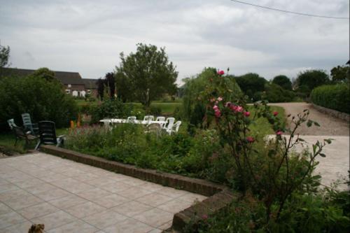 a garden with white tables and chairs and flowers at Le Cardonnet in Pont-Saint-Pierre