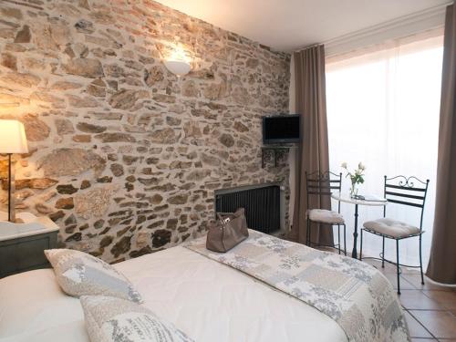 une chambre avec un mur en pierre avec un lit dans l'établissement Hôtel la Bona Casa, à Collioure
