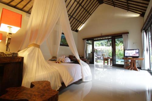 a bedroom with a bed and a television in it at The Forest Villa Ubud in Ubud