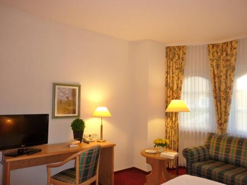 a hotel room with a couch and a television at Landhaus Müritzgarten Hotel garni in Röbel