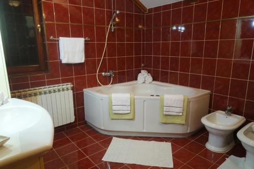 a red tiled bathroom with a tub and a toilet at Luxury house in heart of Old town Bascarsija in Sarajevo