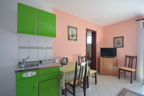 a kitchen with green cabinets and a table with a sink at Apartments Balic in Sveti Stefan