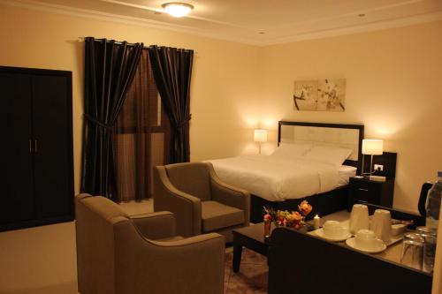 a hotel room with a bed and a table and chairs at Low Light Suites in Al Kharj